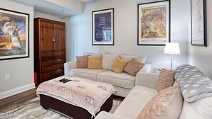 A living room with a sofa, ottoman, and a ceiling fan. There are framed posters on the walls. - 24TH FLOOR WITH STUNNING ENDLESS VIEWS (Holly Hill)