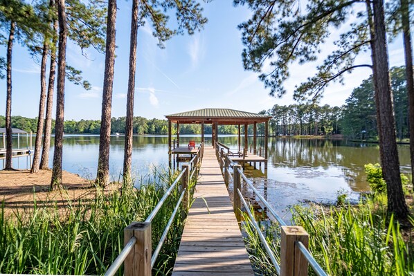 A wooden pier leading to a gazebo by a lake surrounded by tall trees. - Lake Wateree Waterfront Retreat - 6BR w/ Dock, Kayaks, Firepit and Game Room (Winnsboro)