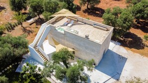 A modern building with a flat roof, a swimming pool, and a covered outdoor area with seating. - Country house with a view of the sea (Puglia)