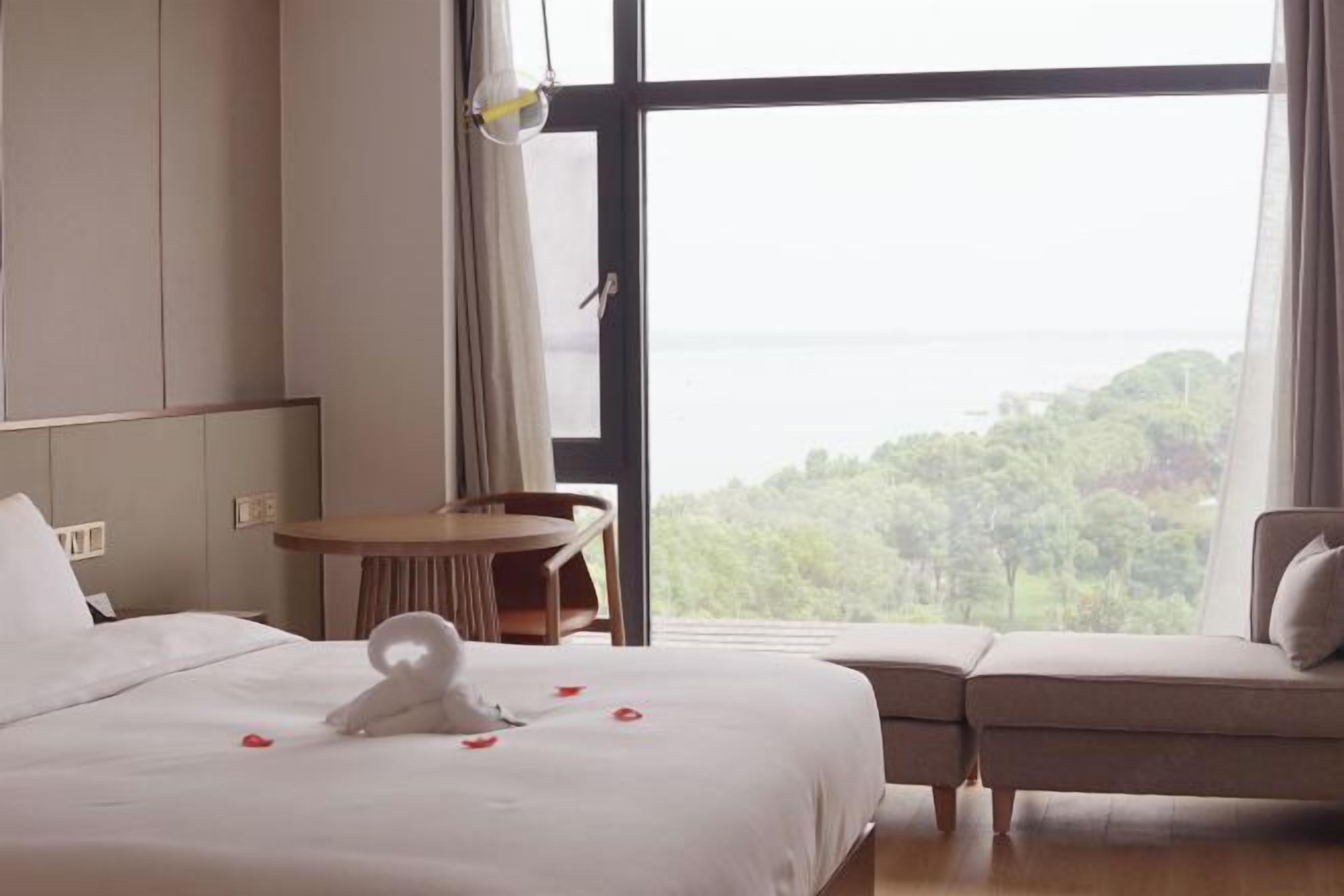 Habitación de hotel con cama, sofá, una mesita y vista al mar.