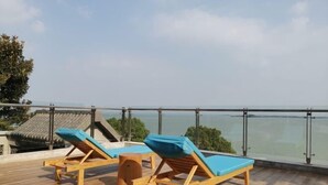 Una terraza en la azotea con dos sillones de madera y una pequeña mesa redonda.