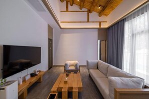 Una sala de estar moderna con un televisor de pantalla plana, una mesa de centro de madera, un sofá y una silla.