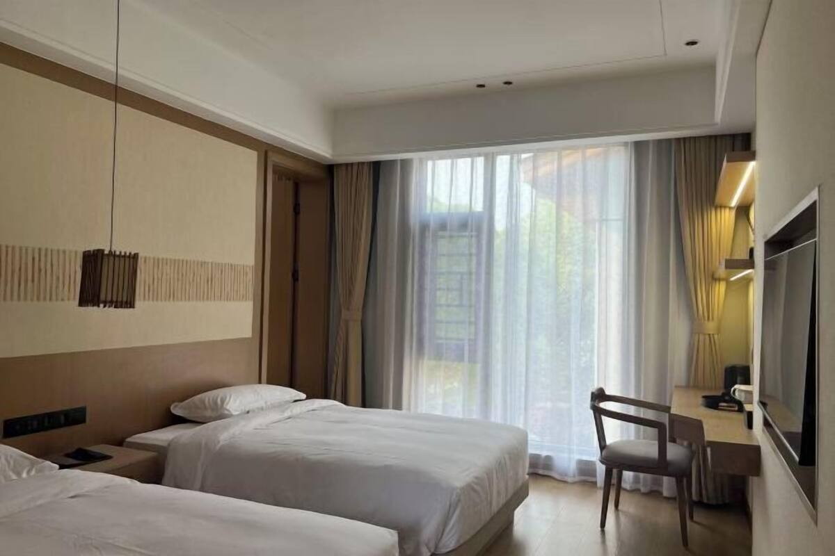 Habitación de hotel con dos camas, un escritorio y una silla.