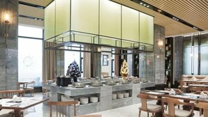 Un restaurante moderno con una isla central, asientos alrededor y un amplio ventanal que proporciona luz natural.