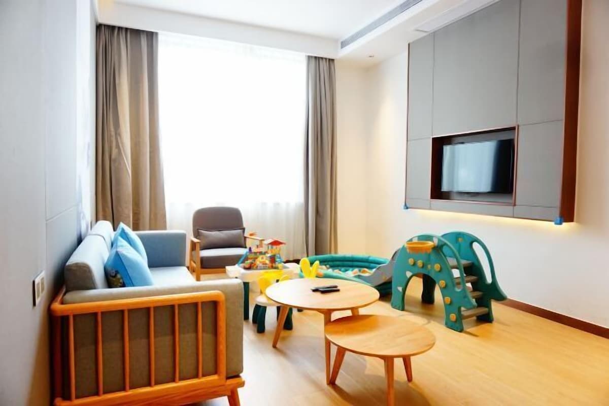 Una sala de estar moderna con sofá, sillón, mesa de centro y zona de juegos para niños.
