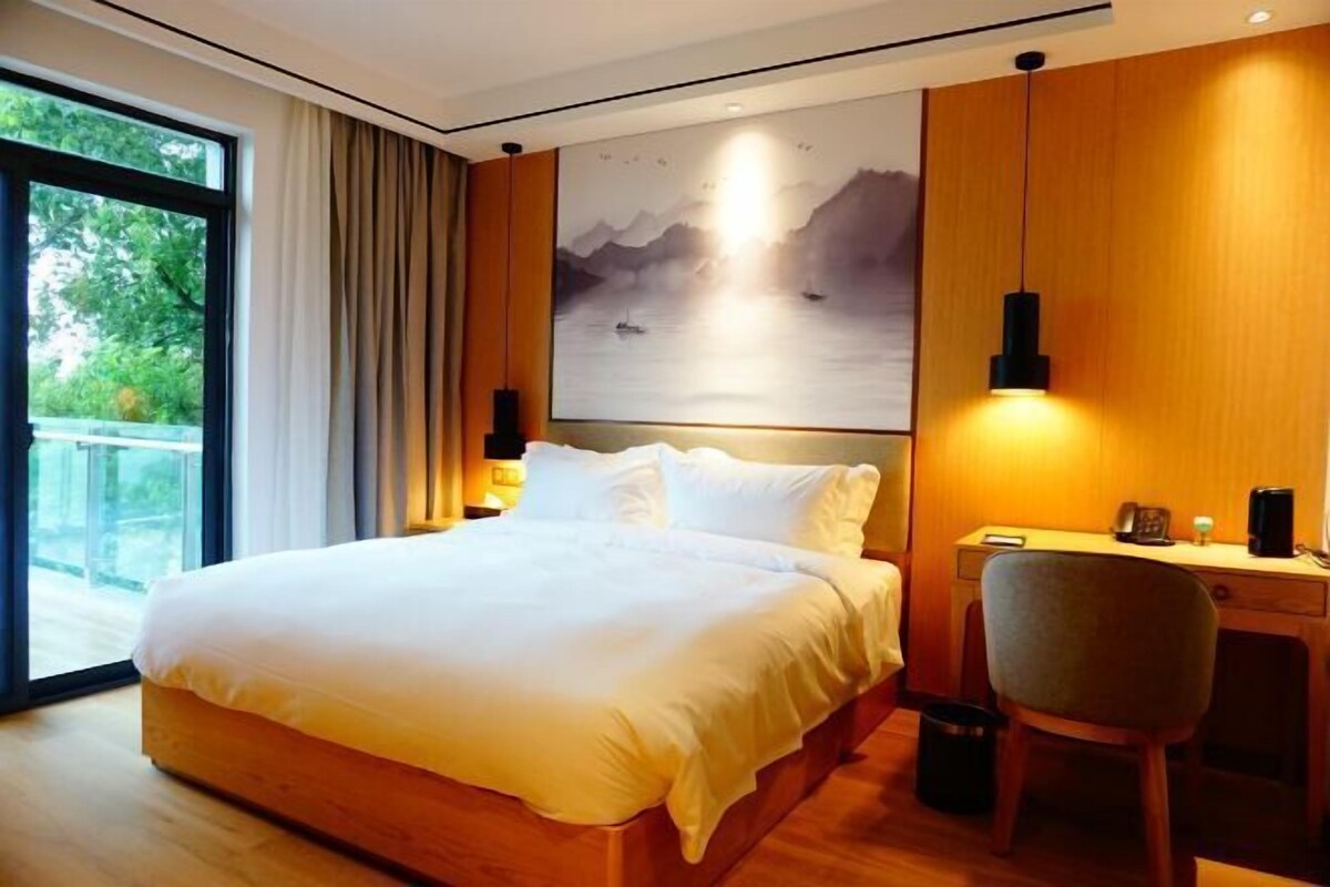 Una habitación de hotel moderna con una cama grande, un escritorio y vistas al exterior.