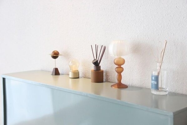 Une table au design minimaliste agrémentée de divers objets décoratifs, notamment une bougie, un diffuseur et un diffuseur à tiges.