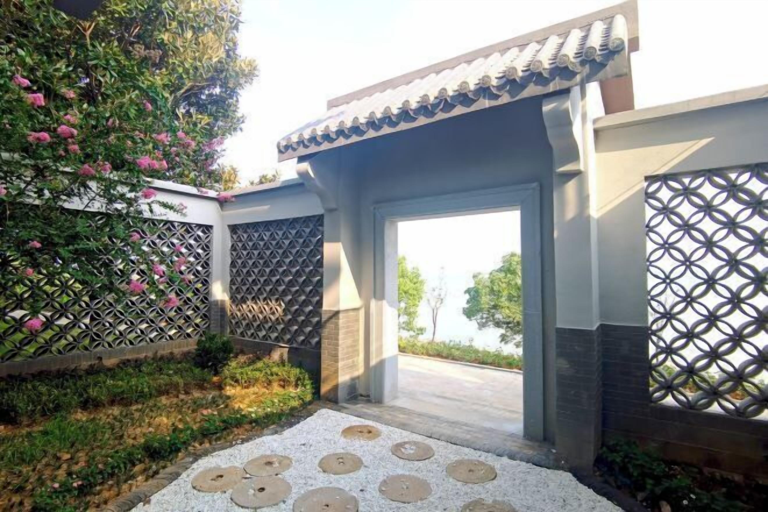 A traditional-style entrance with a tiled roof, a lattice fence, and a pathway leading to a building.