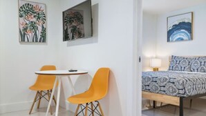 A room with a bed, two chairs, a small table, and artwork on the walls. - Miami Suite 308 (Miami)