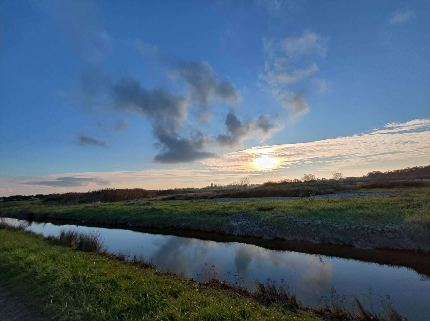 A calm river with grassy banks and a clear sky.