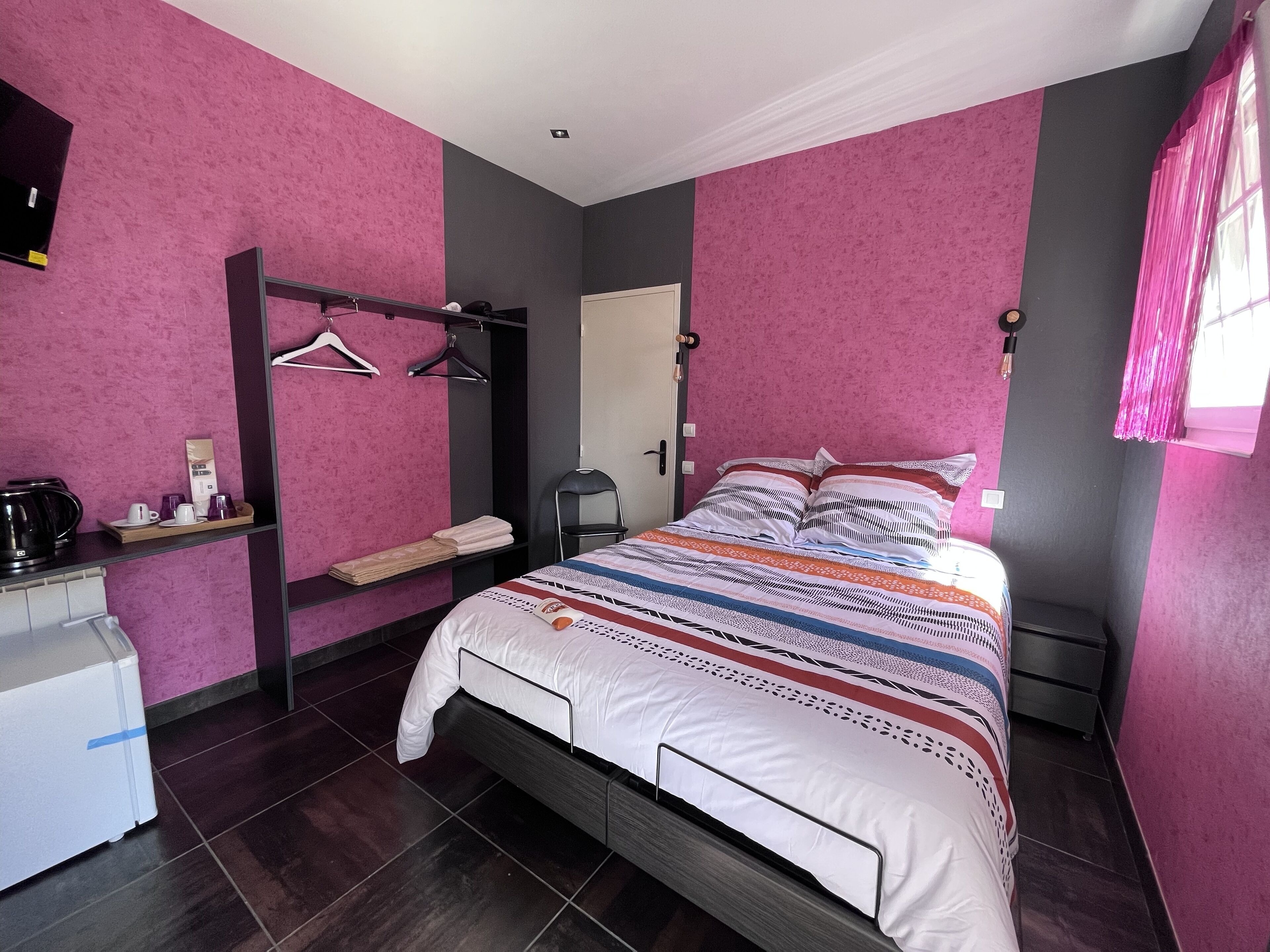 Un dormitorio con cama, armario, escritorio con tetera y silla.
