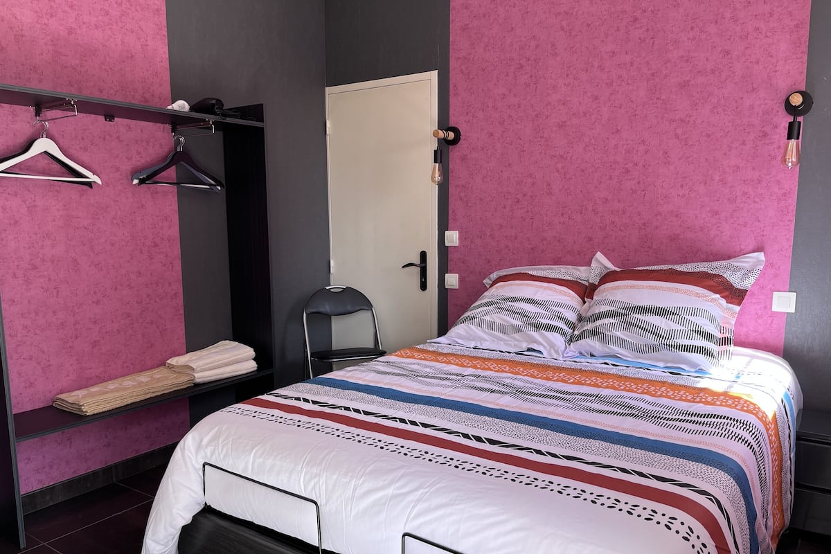 Une chambre à coucher comprenant un lit, une chaise, une armoire et une étagère avec des serviettes.
