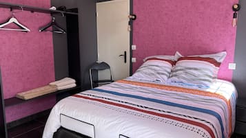 Een slaapkamer met een bed, een stoel, een kledingkast en een plank met handdoeken.