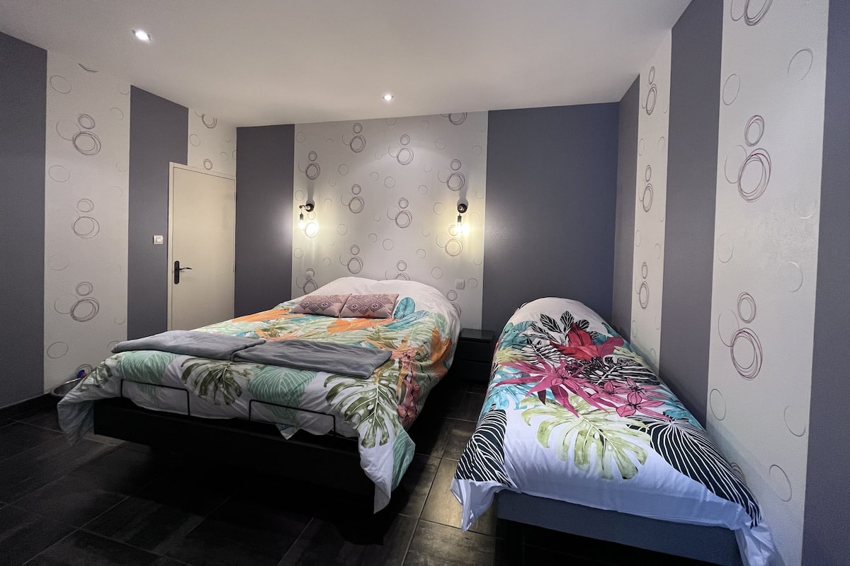 Une chambre moderne avec deux lits simples, une porte et des lampes fixées au mur.
