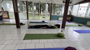 Een ruime binnenruimte met meerdere yogamatten en fitnessballen, wat duidt op een fitness- of wellnesscentrum.