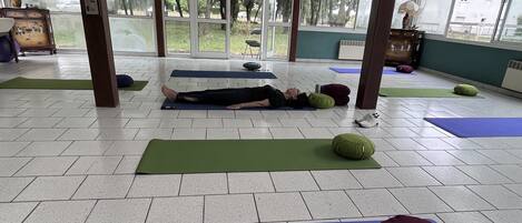 Un grand espace intérieur équipé de plusieurs tapis de yoga et de ballons d’exercice, ce qui laisse supposer qu’il s’agit d’un centre de remise en forme ou de bien-être.