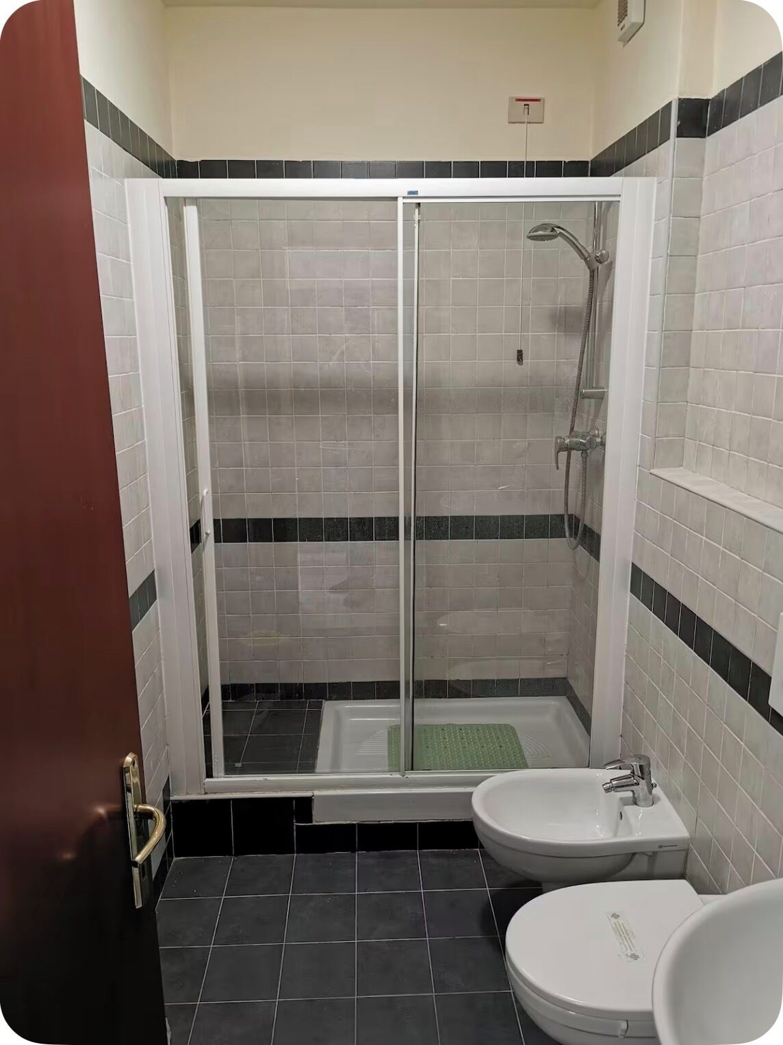 A bathroom with a glass-enclosed shower, a sink, and a toilet.