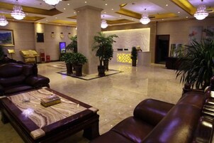 Un hall de hotel con asientos de cuero, un mostrador de recepción y plantas en macetas.