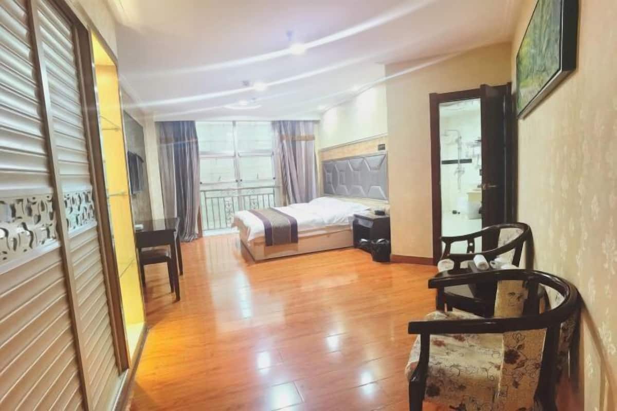 Quarto de hotel com cama, mesa de cabeceira, cadeira e vista para a varanda.