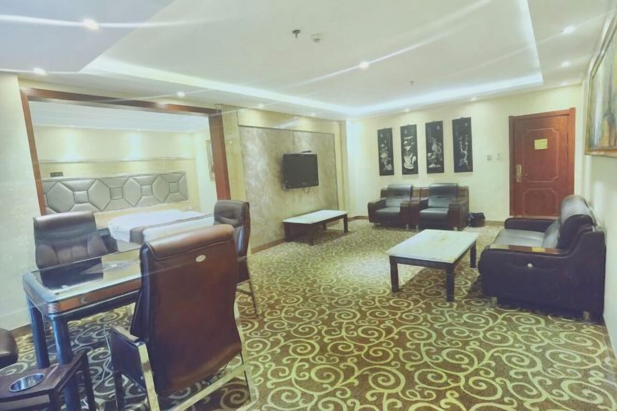 A hotel lobby with a seating area, a reception desk, and a television mounted on the wall.