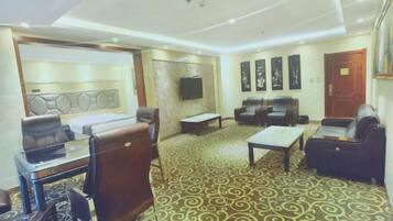 A hotel lobby with a seating area, a reception desk, and a television mounted on the wall.