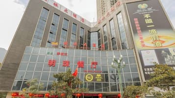 A modern building with a glass facade, signage for '明珠餐厅' (Ming Zhu Restaurant), and a large advertisement on the side.