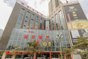 A modern building with a glass facade, signage for '明珠餐厅' (Ming Zhu Restaurant), and a large advertisement on the side.