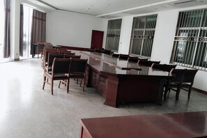 A conference room with a long table and chairs, large windows with metal bars, and a high ceiling. - Bright Pearl Hotel (Longnan)
