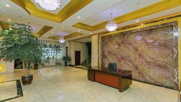 A lobby with a reception desk, a large marble wall, and a chandelier.