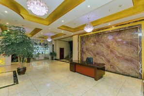 A lobby with a reception desk, a large marble wall, and a chandelier. - Bright Pearl Hotel (Longnan)