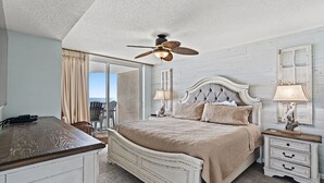 Ein Schlafzimmer mit Bett, Nachttischen, Deckenventilator und Blick ins Freie.
