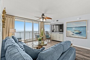 Ein modernes Wohnzimmer mit einer großen Couch, einem Esstisch mit Stühlen und einem Deckenventilator.