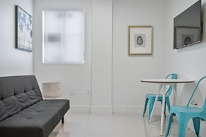 A modern living room with a grey sofa, a small round table, and two turquoise chairs. - Miami Suite 310 (Miami)