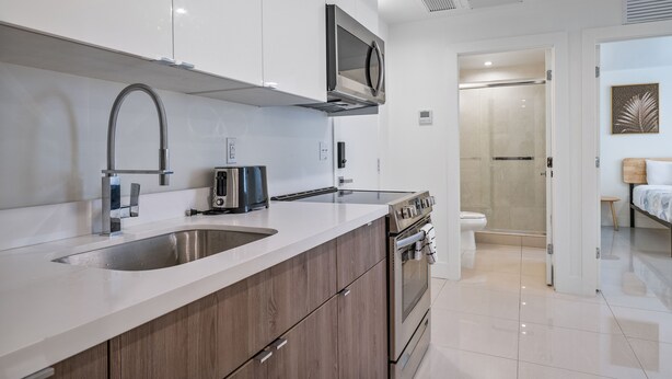 A modern kitchen with stainless steel appliances, a double sink, and wooden cabinets. - Miami Suite 310 (Miami)