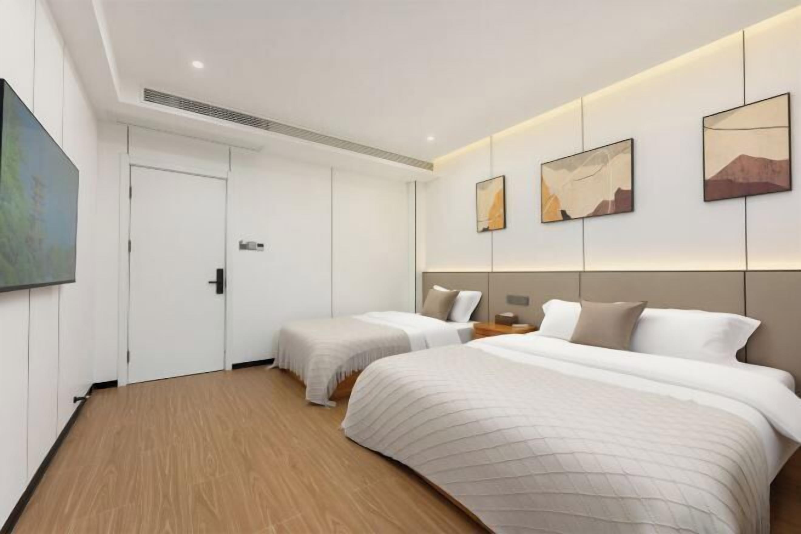 Une chambre d’hôtel avec deux lits, une grande peinture sur le mur de gauche et trois œuvres d’art encadrées sur le mur.