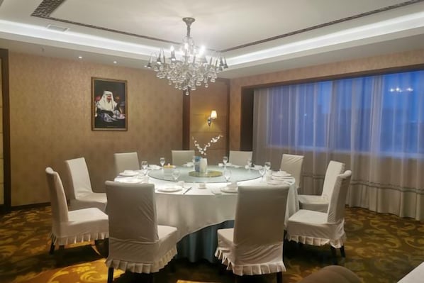 A conference room with a round table, white chairs, a chandelier, a painting on the wall, and a window with curtains. - International Academic Exchange Center (Yuntang Campus Hotel, CSUST) (Changsha)