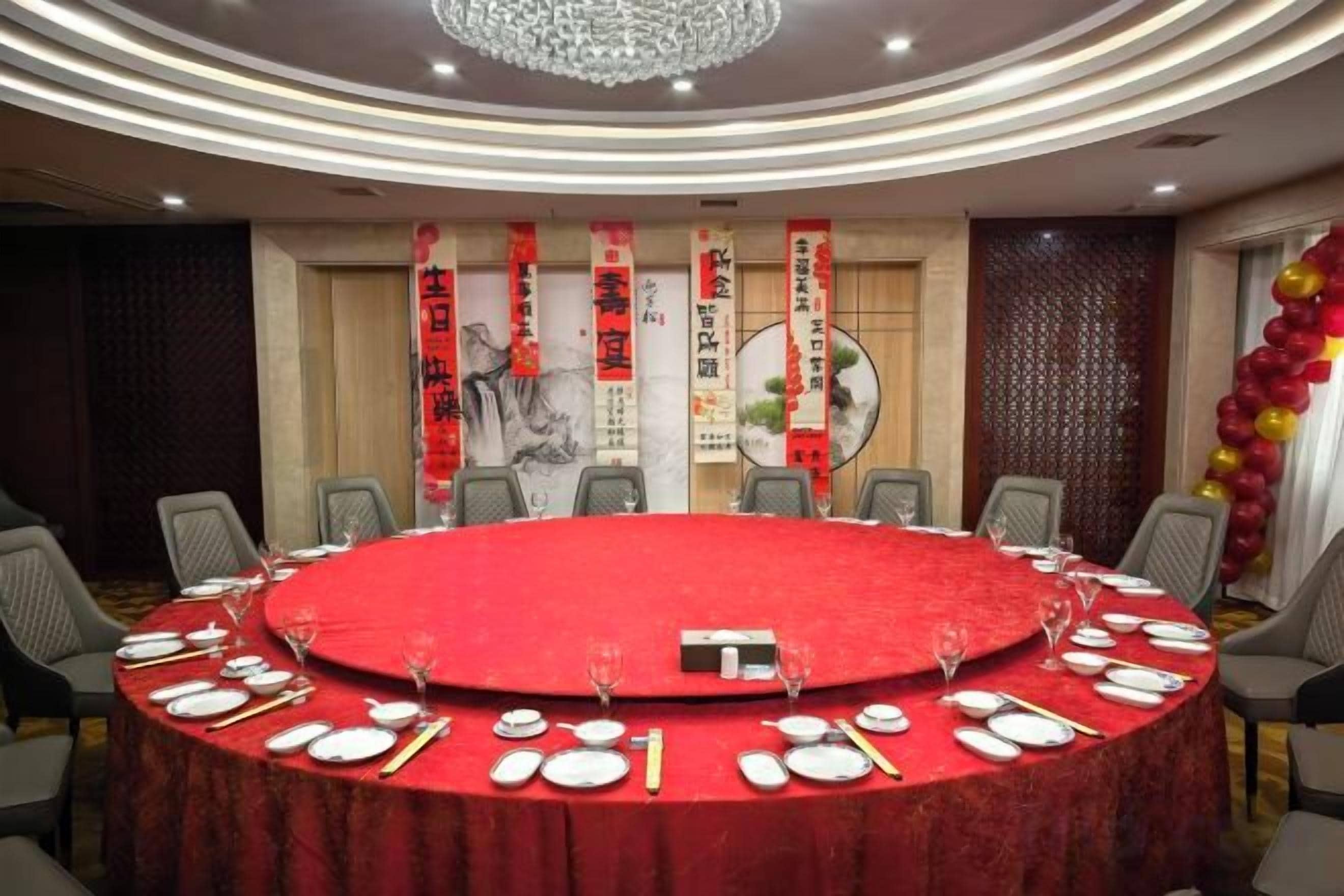 Un salón de conferencias con una mesa redonda, sillas y un mantel rojo.