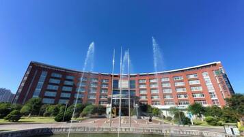 A large building with a fountain in front, surrounded by greenery.
