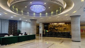 A hotel lobby with a circular ceiling design, a reception desk, and a mural. - International Academic Exchange Center (Yuntang Campus Hotel, CSUST) (Changsha)