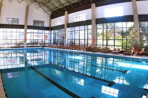 An indoor swimming pool with clear water, multiple lanes, and sunlit windows.
