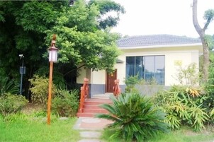 A house with a red pathway leading to the entrance, surrounded by greenery.