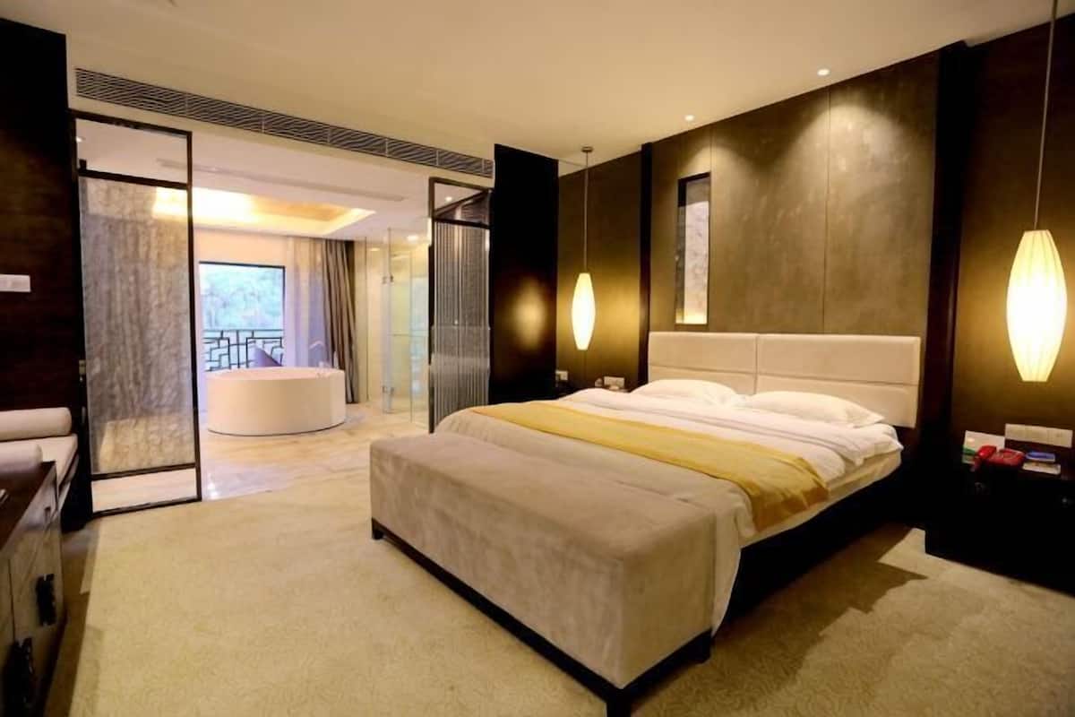 Quarto de hotel com uma cama grande, uma área de estar separada e vista para uma varanda.
