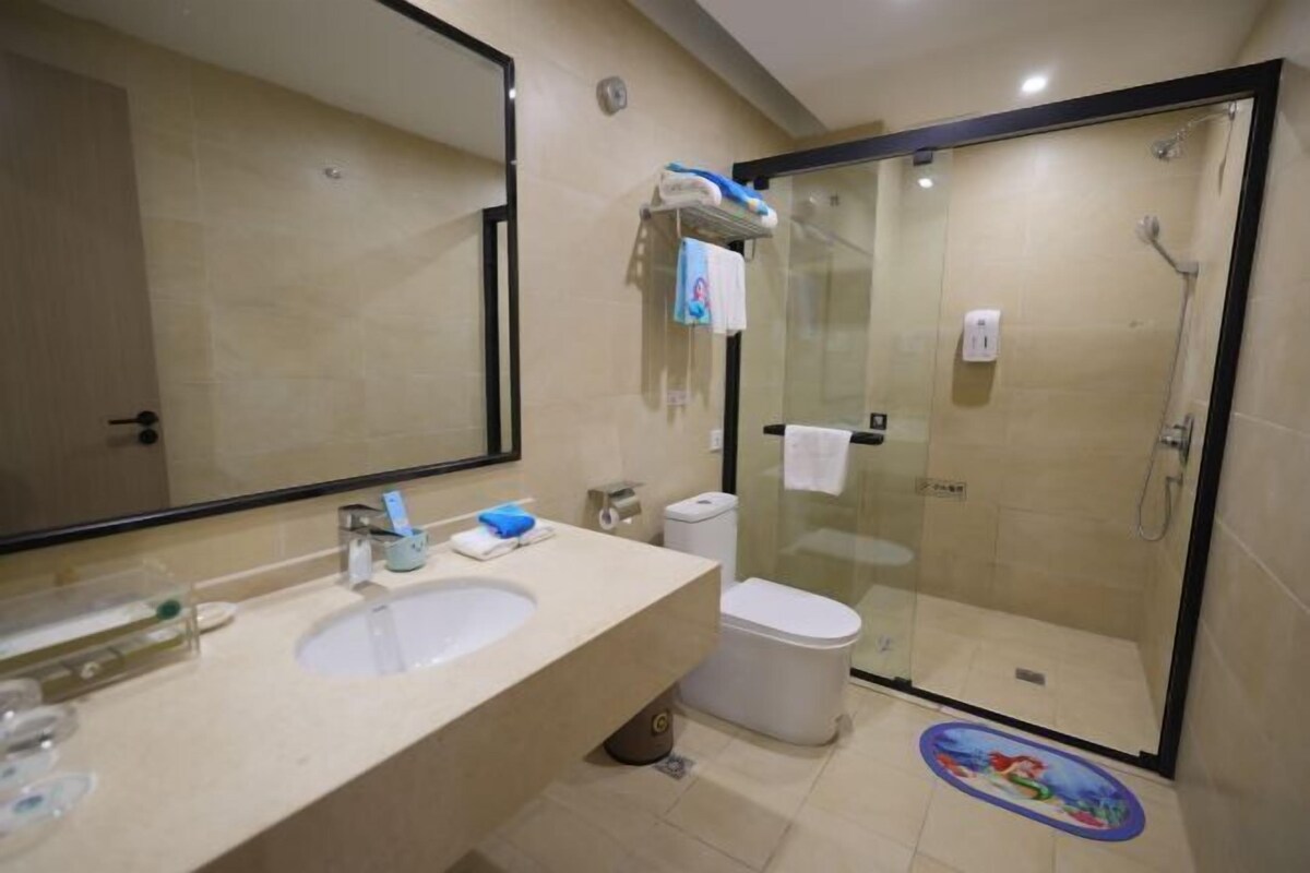 A modern bathroom with a large mirror, a sink, a toilet, and a glass-enclosed shower.
