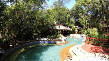 A pool surrounded by trees, a wooden deck, and a gazebo.