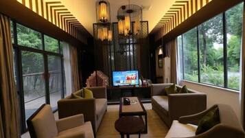 Una sala de estar moderna con un televisor grande, asientos cómodos y ventanas amplias que ofrecen vistas al exterior.