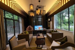 Una sala de estar moderna con un televisor grande, asientos cómodos y ventanas amplias que ofrecen vistas al exterior.
