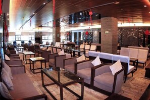 A hotel lobby with seating areas, a bar, and a decorative wall.
