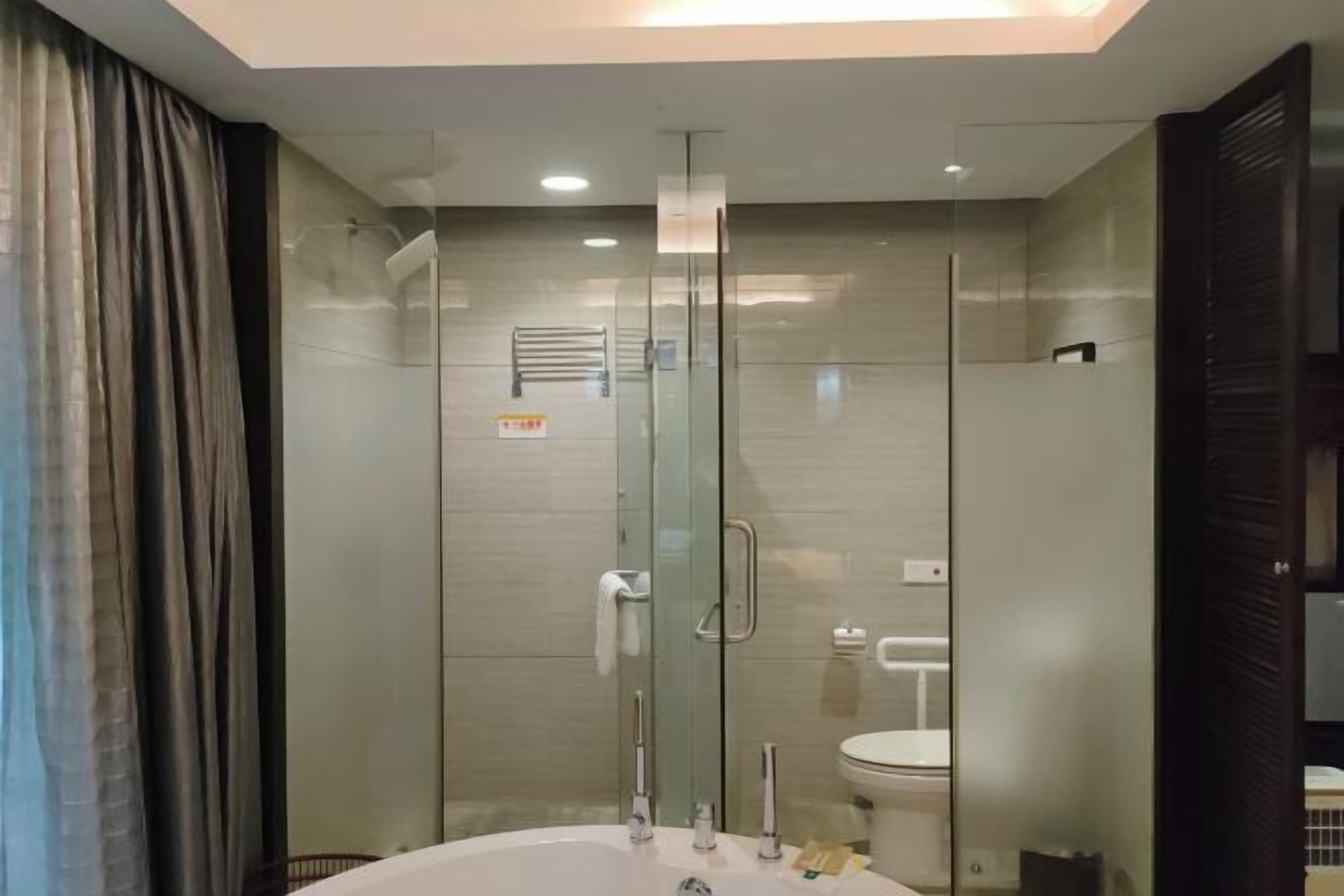 A modern bathroom with a glass-enclosed shower, a bathtub, and a toilet.