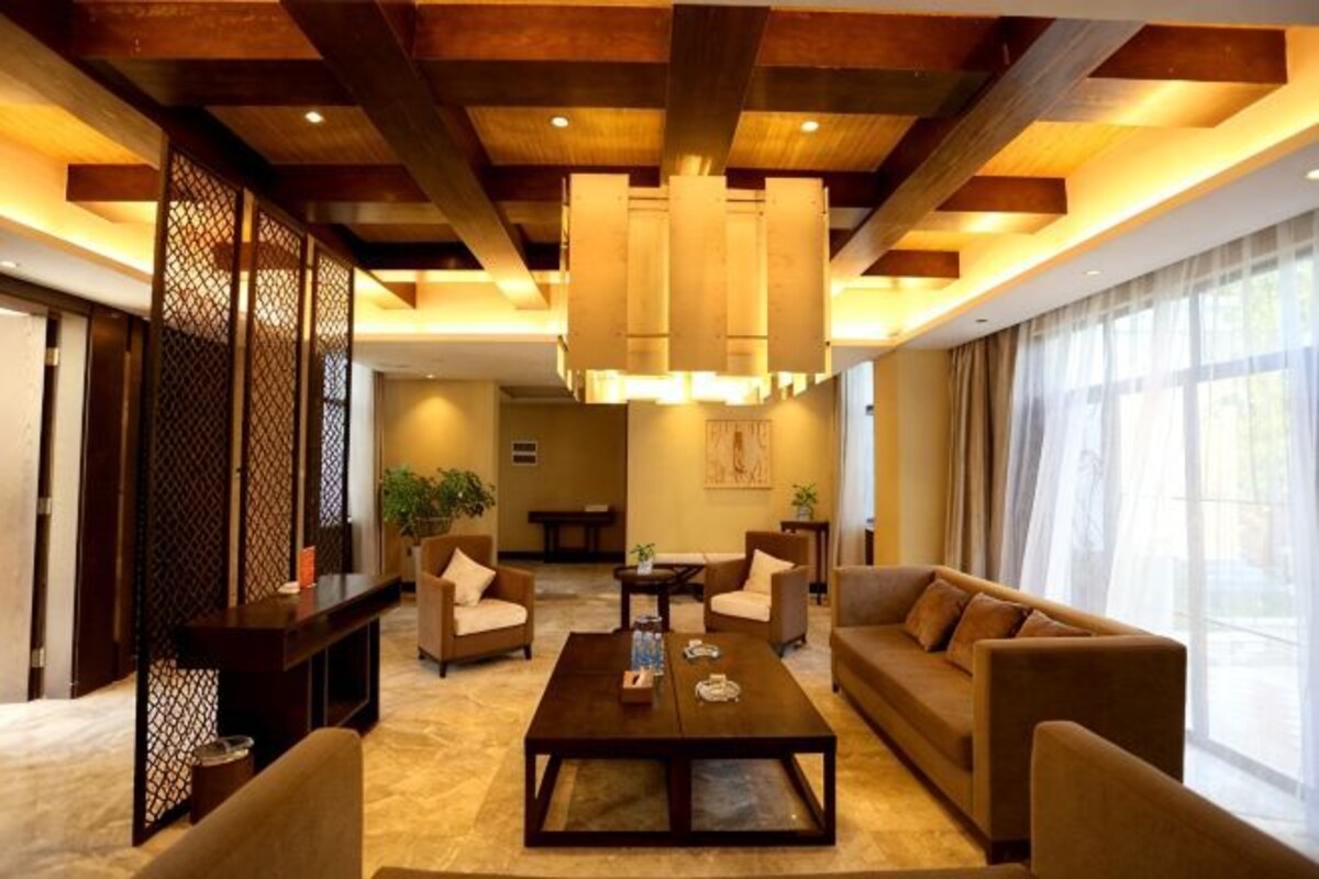 A spacious living room with a large sofa, a coffee table, and a hanging light fixture.