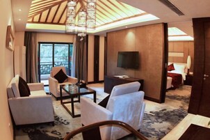Una habitación de hotel moderna con un televisor grande, asientos cómodos, una araña y vistas al exterior.